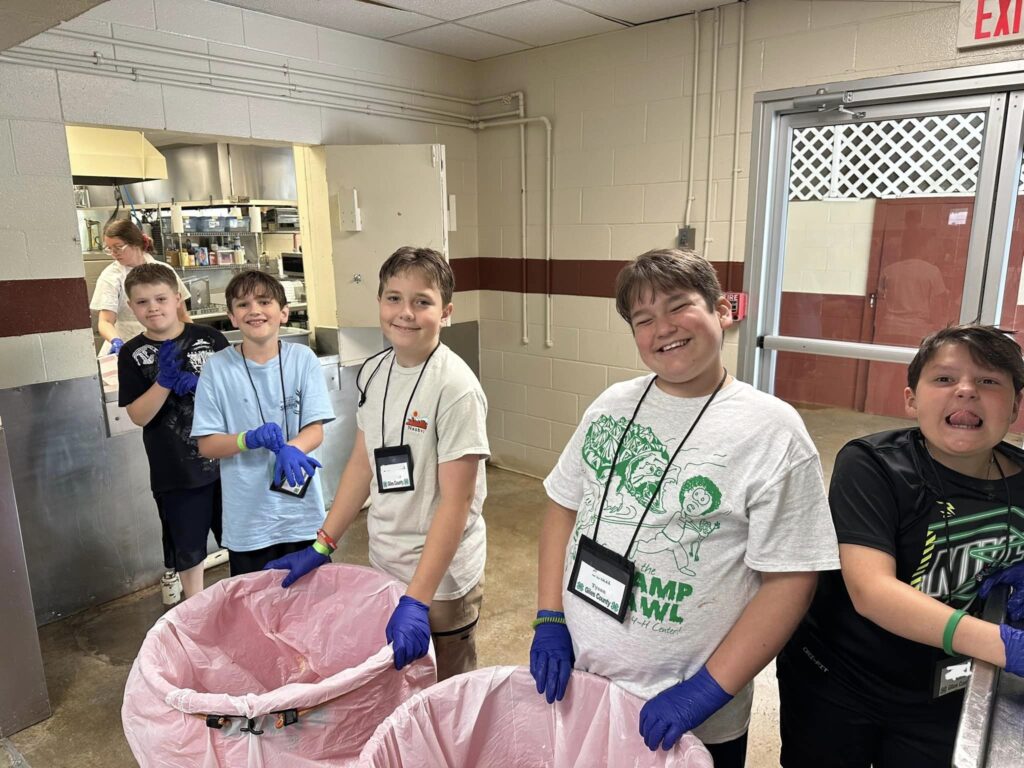 Kids standing behind trash cans.