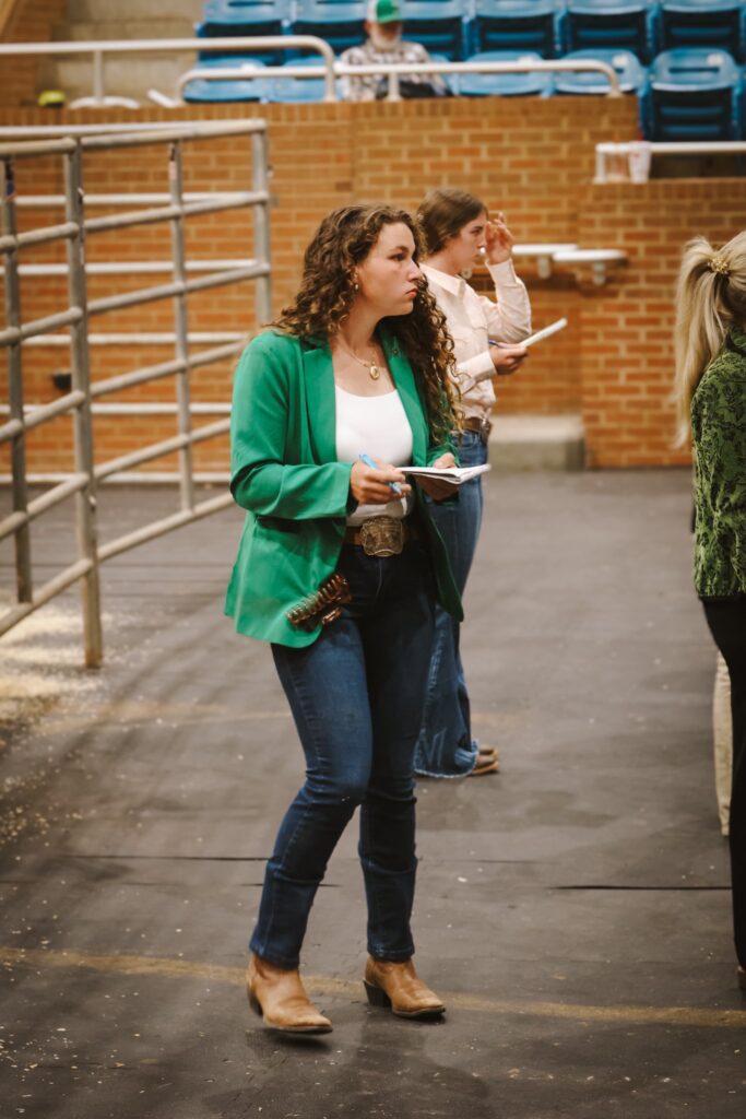 4-H'er standing and looking at livestock.